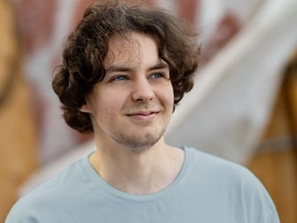 Gymnasiekille med brunt lockigt hår och ljusblå t-shirt