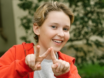 Glad kille med blont hår och röd munkjacka. 