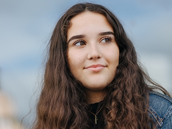 Tjej med långt mörkt hår tittar åt sidan