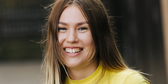 Tjej med långt brunt hår och gul topp