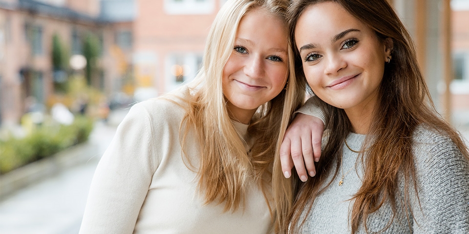 En blond och brunhårig flicka som ler