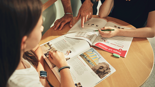 Bord i ett klassrum med två av Sanomas böcker uppslagna