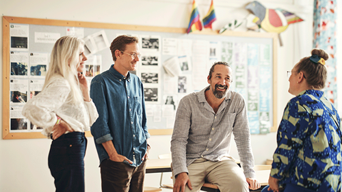 Fyra lärare står eller sitt er bredvid varandra i ett klassrum