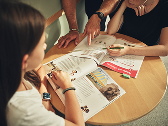 Elever och lärare samarbetar kring läromedel vid ett gemensamt bord