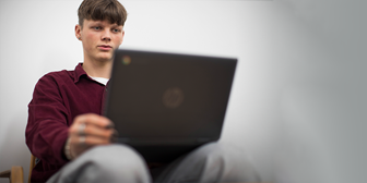 Kille sitter vid en laptop