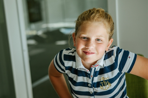 Tjej i randig tröja står vid en dörröppning